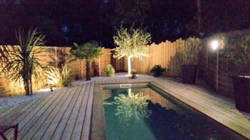 une arrière-cour avec une piscine la nuit dans l'établissement Pretty house with pool and large terrace - Bassin d'Arcachon, à Arès