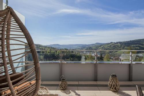 a balcony with a rattan chair and a view at Apartview Bukowa III by Rent like home in Wisła