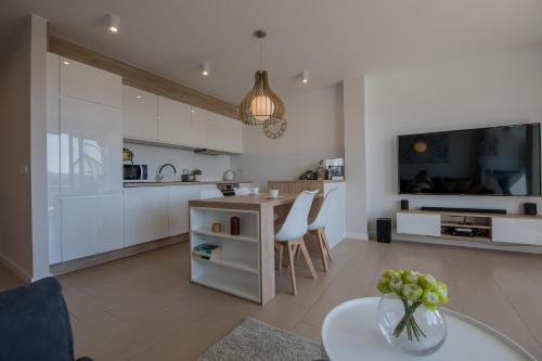 a kitchen and living room with white cabinets and a table at Apartview Bukowa III by Rent like home in Wisła