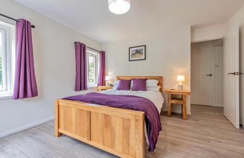 a bedroom with a large bed with purple sheets at Finest Retreats - Blaen Ddol in Betws-y-coed