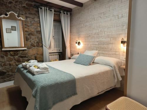a bedroom with two beds and a stone wall at A Casa Da Canle in Braño
