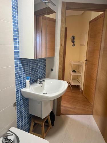 a bathroom with a white sink and a mirror at Las Catedrales ático Oceano VI in Barreiros