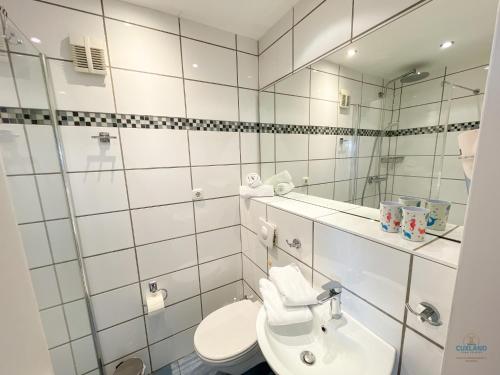 Baño blanco con lavabo y espejo en Haus Atlantic Döse Wohnung 708, en Cuxhaven
