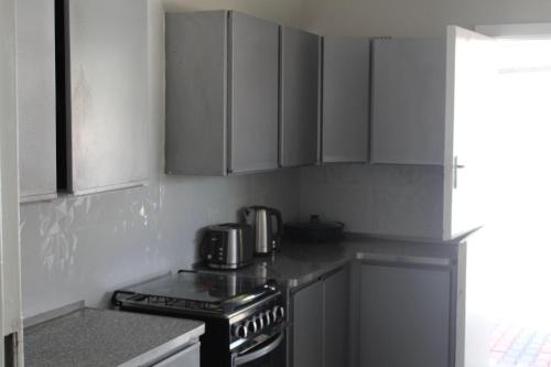 a kitchen with white cabinets and a stove top oven at One03 Guest house in Harare