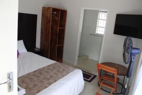 a bedroom with a bed and a chair and a television at One03 Guest house in Harare
