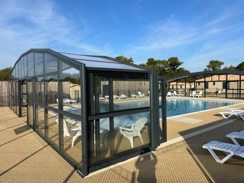 une maison en verre avec une piscine et deux chaises dans l'établissement Cottage 79 Landes nature, à Saubrigues