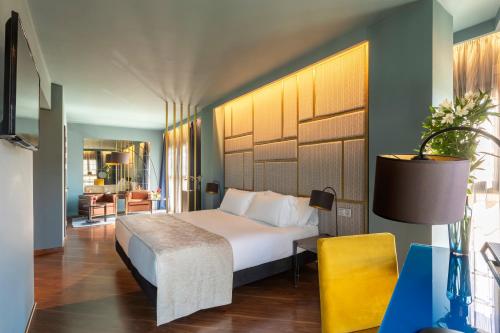 a bedroom with a white bed and a yellow chair at Pamplona Catedral Hotel in Pamplona