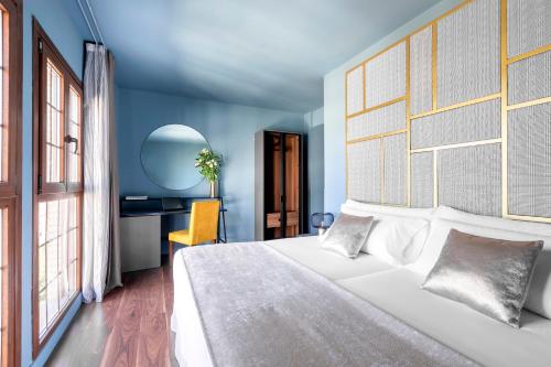 a bedroom with a large white bed and a desk at Pamplona Catedral Hotel in Pamplona