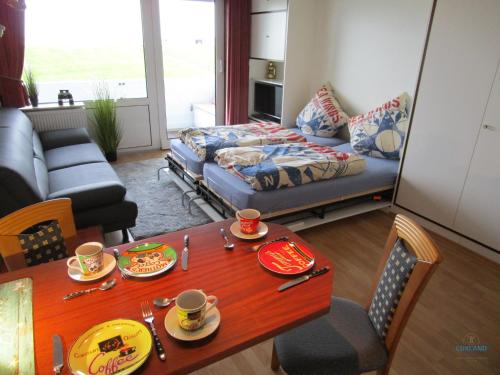a living room with a bed and a table with cups and plates at Ferienwohnung 223 Haus Nautic in Cuxhaven