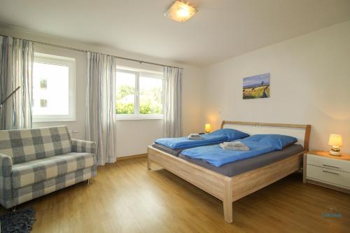 ein Schlafzimmer mit einem Bett, einem Stuhl und einem Fenster in der Unterkunft Residenz Hohe Lith Wohnung 04 01 in Cuxhaven