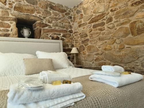 a bedroom with towels on a bed with a stone wall at A Casa Da Canle in Braño