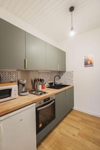 une cuisine avec des armoires blanches et un four à plaques de cuisson dans l'établissement L'Ecume - Maison avec terrasse à 50m de la mer, à Étretat