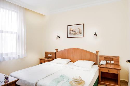 a bedroom with a bed and two tables and a window at Amber-Rose Apart Hotel in Alanya