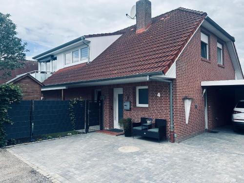 a red brick house with a car parked in the driveway at Ferienwohnung Noa 15203 in Leer