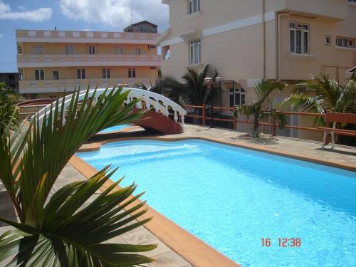 弗利康弗拉克Ideally Located, Fully Furnished, Air Cond Apartment In Flic En Flac !ONLY 5 mins walk to the beach的建筑物前的一个大型蓝色游泳池