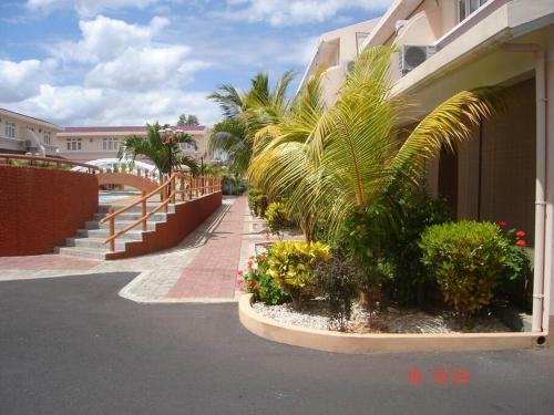 弗利康弗拉克Ideally Located, Fully Furnished, Air Cond Apartment In Flic En Flac !ONLY 5 mins walk to the beach的街道旁种有棕榈树和植物的建筑