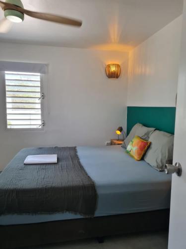 a bedroom with a bed with a green headboard and a window at 13 Palm Tree in Kralendijk