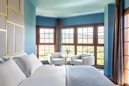 a bedroom with a bed and a table and windows at Pamplona Catedral Hotel in Pamplona