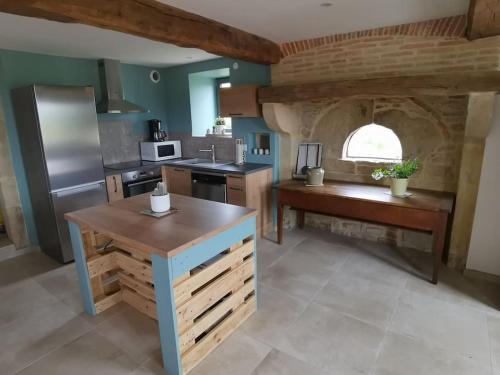 une grande cuisine avec des comptoirs en bois et une grande fenêtre dans l'établissement Fermette Brionnaise, à Saint-Laurent-en-Brionnais