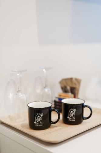two black coffee mugs sitting on a wooden tray at It's Room Naples in Naples