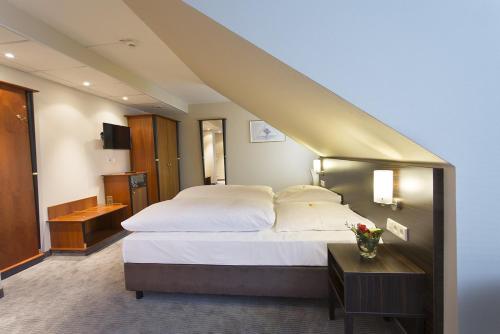a hotel room with a large bed and a staircase at Erikson Hotel in Sindelfingen