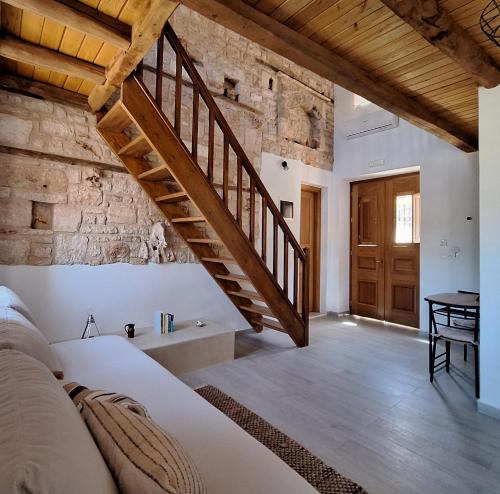 a bedroom with a staircase and a stone wall at To Pefko - Mezzanines - in Meyisti