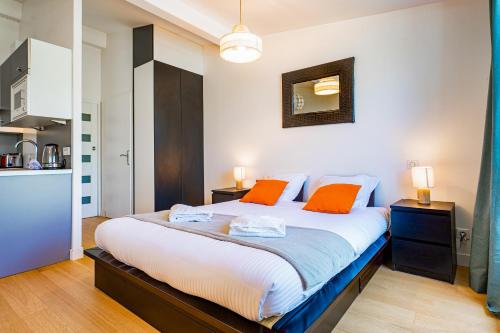 a bedroom with a large bed with two orange pillows at Superbe Studio Climatise avec Terrasse en Hyper Centre in Bordeaux