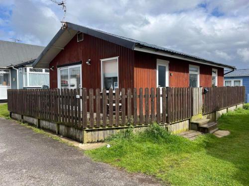 a red house with a wooden fence in front of it at Seaside Escape Chalet in Bridlington south shore in Bridlington