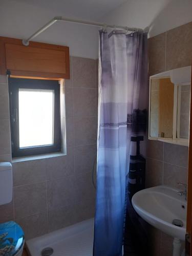 a bathroom with a blue shower curtain and a sink at Orchid in Selce