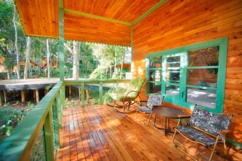 a porch of a wooden house with chairs and tables at Măng Đen Treehouse Village Resort & Zipline in Kon Von Kla