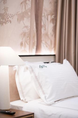 a bed with a white pillow and a picture on the wall at La Fe Boutique Hotel Sarande in Sarandë