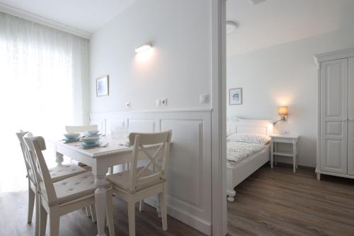 a white room with a table and chairs and a bed at Angele Pihenőház in Balatonszárszó