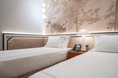two beds in a room with a phone on a table at La Fe Boutique Hotel Sarande in Sarandë