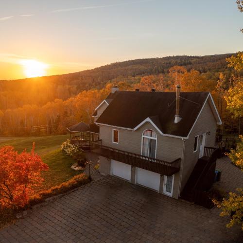 eine Luftansicht eines Hauses mit Sonnenuntergang im Hintergrund in der Unterkunft Intimate Apartment with Scenic Views in Baie-Saint-Paul