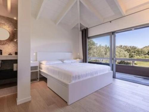 - une chambre blanche avec un grand lit et une grande fenêtre dans l'établissement LE PETIT DOMAINE DE SPERONE, à Bonifacio