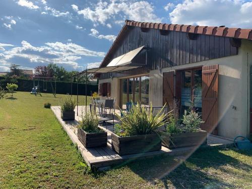 une maison avec une terrasse couverte ornée de plantes dans une cour dans l'établissement Gîte Convivial en Ardèche Verte, à Cheminas