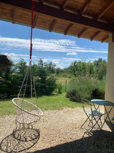 une balançoire suspendue à un porche avec une table dans l'établissement Gîte Convivial en Ardèche Verte, à Cheminas