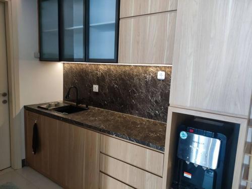 a kitchen with a sink and a counter with a tv at Apartment Benson Tower 2 Bed Room by Lavida in Surabaya