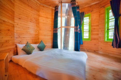 a bedroom with a bed in a wooden room at Măng Đen Treehouse Village Resort & Zipline in Kon Von Kla