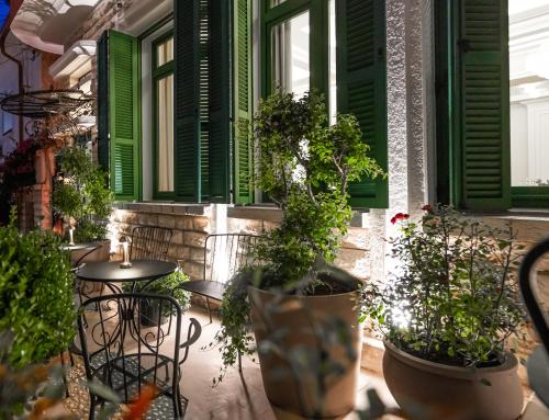 a patio with green shuttered windows and potted plants at La Fe Boutique Hotel Sarande in Sarandë