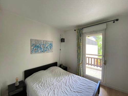 une chambre avec un lit et une grande fenêtre dans l'établissement Appartement Idéal : Proche Port, Plages et Centre, Wifi, Parking, Balcon - FR-1-413-97, à Capbreton