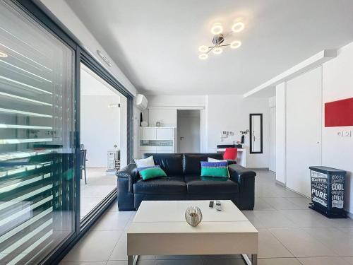 un salon avec un canapé noir et une table dans l'établissement T2 Moderne avec Grande Terrasse, Parking et Proche Mer - Idéal 2 à 4 Pers - FR-1-770-19, à La Ciotat