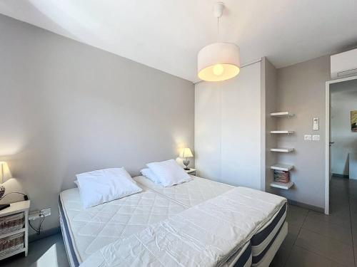 une chambre avec un grand lit avec des draps blancs dans l'établissement T2 Moderne avec Grande Terrasse, Parking et Proche Mer - Idéal 2 à 4 Pers - FR-1-770-19, à La Ciotat