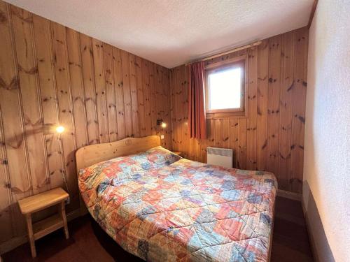 une chambre avec un lit dans une pièce aux murs en bois dans l'établissement Appartement cosy 5 pers à 20m des pistes et commerces, balcons, parking couvert - FR-1-180-601, à Les Allues