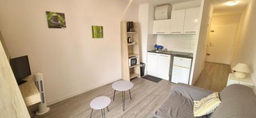Il comprend un salon avec un canapé et deux tables ainsi qu'une cuisine. dans l'établissement Joli studio cosy design , 4 pers, parking, à La Grande Motte