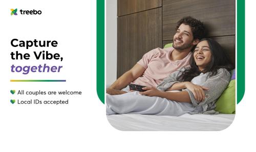a man and a woman sitting on a bed at Treebo Grand Vistara Airport Suites in Cochin