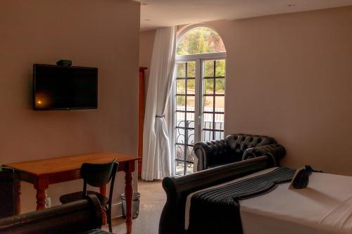 a room with a bed and chairs and a window at Vila Pugliesi Hotel Boutique in Lençóis
