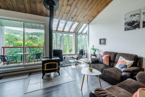 a living room with a couch and a fireplace at Superbe condo face aux pentes de ski Stoneham!!! in Stoneham