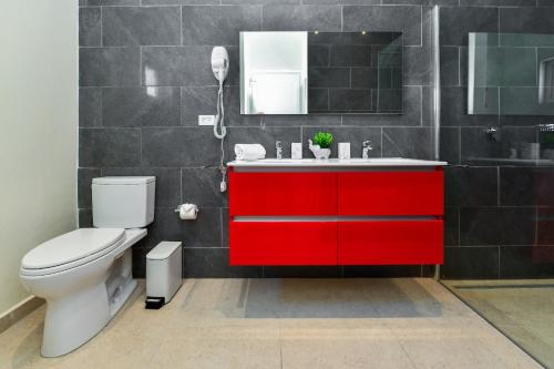 Un baño con un lavabo rojo y un inodoro. en Swiss Paradise Aruba Luxury Collection, en Palm-Eagle Beach
