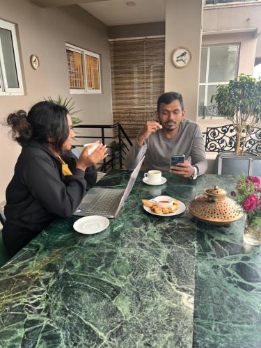 a man and woman sitting at a table with a laptop at Sunset Villa in Coonoor